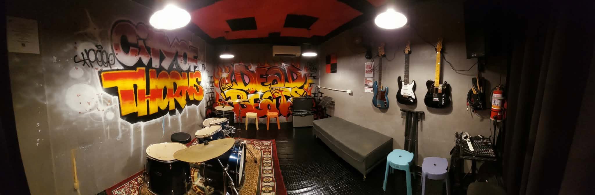 Inside Dead Beats Music Studio showing drums, guitar wall, and graffiti art